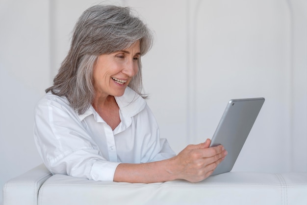 Retrato, de, sonriente, mujer mayor, usar la computadora portátil, en casa