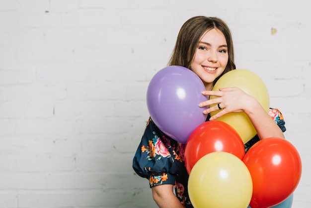 Retrato sonriente de una niña adolescente sosteniendo globos