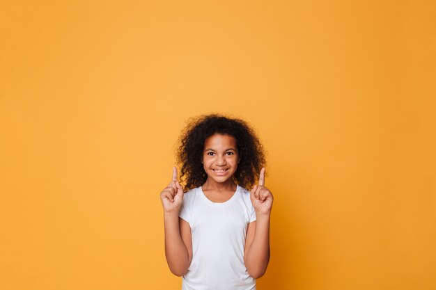 Retrato de una sonriente niña africana señalando con el dedo