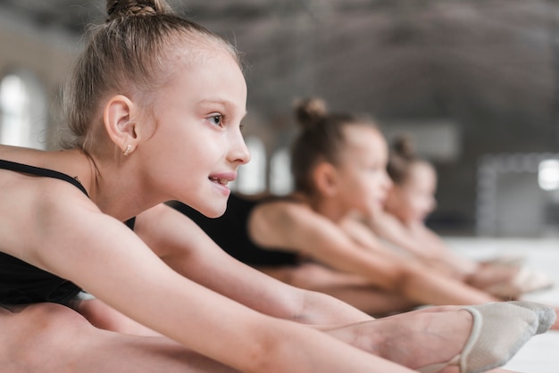 Retrato de sonriente niña bailarina con sus amigos que se extiende