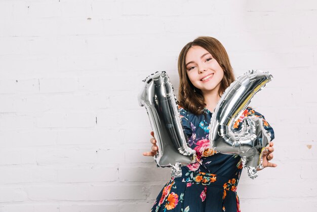 Retrato sonriente de una niña mostrando el globo numérico número 14