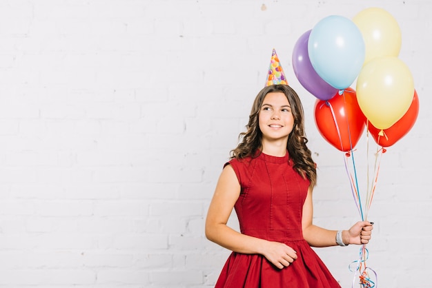 Retrato sonriente de una niña sosteniendo globos de colores en la mano