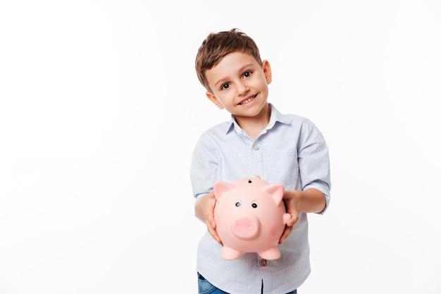 Retrato de un sonriente niño lindo con hucha