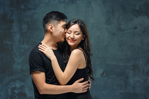 Retrato de la sonriente pareja coreana en un gris