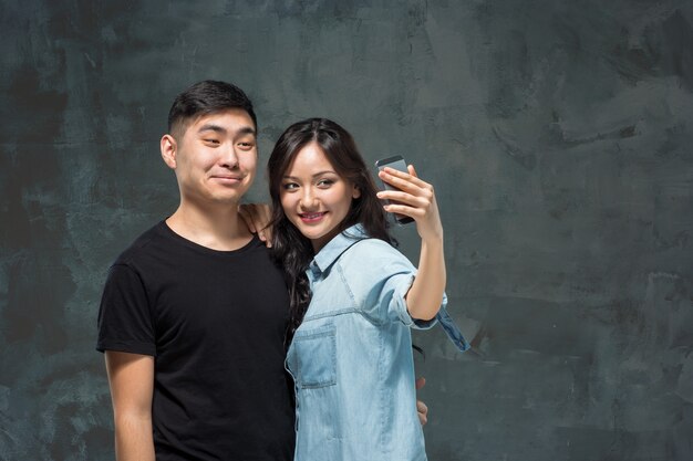 Retrato de la sonriente pareja coreana en un gris