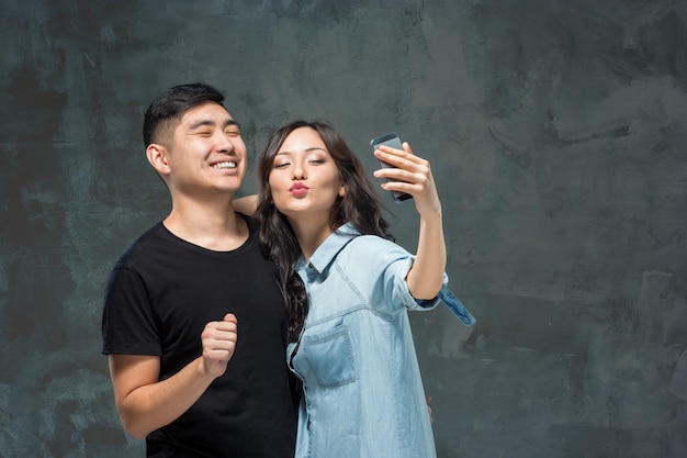 Retrato de la sonriente pareja coreana en un gris