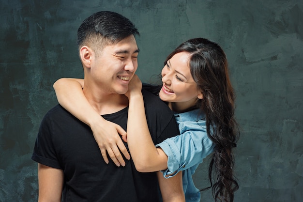 Retrato de la sonriente pareja coreana en una pared gris