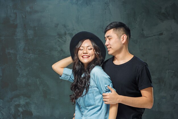 Retrato de la sonriente pareja coreana en una pared gris