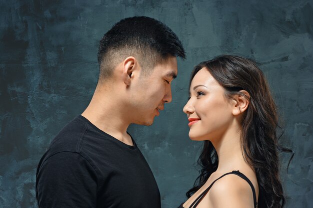 Retrato de la sonriente pareja coreana en una pared gris