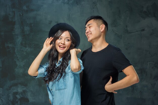 Retrato de la sonriente pareja coreana en una pared gris