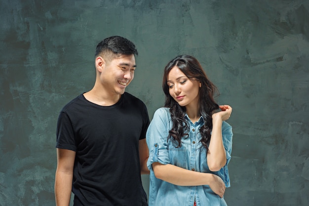 Retrato de la sonriente pareja coreana en una pared gris