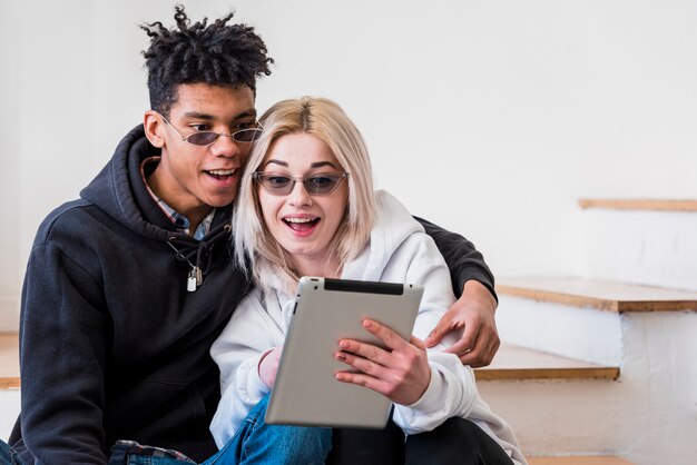 Retrato de la sonriente pareja joven interracial mirando tableta digital