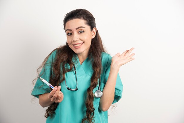 Retrato de sonriente trabajadora sanitaria posando con termómetro.