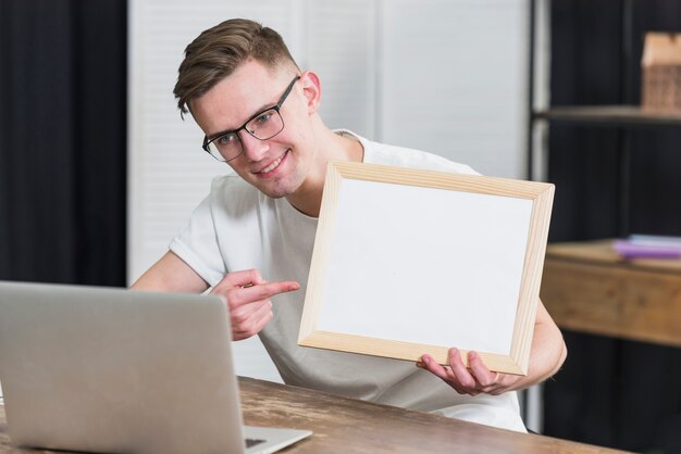 Retrato sonriente de un video del hombre joven que charla mostrando el marco de madera