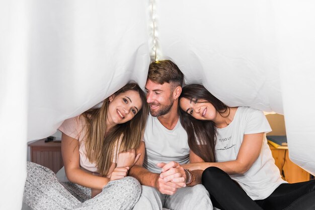 Retrato de la sonrisa de dos amigas que se sientan con el hombre