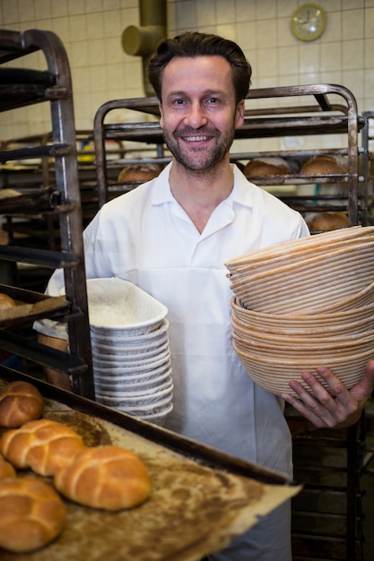 Retrato de la sonrisa panadero que sostiene la pila de la bandeja y cajas