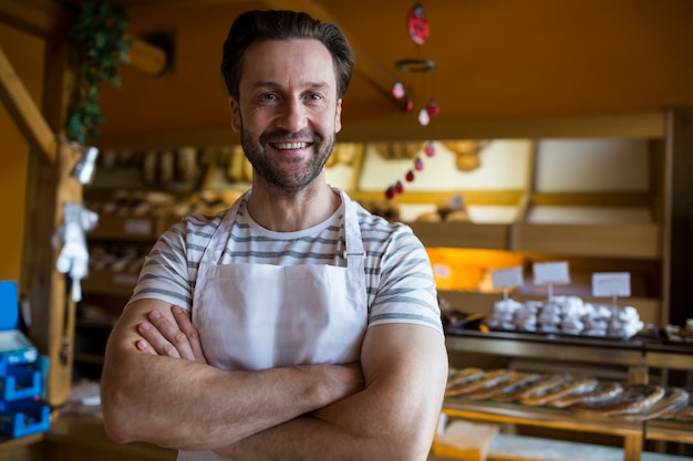 Foto gratuita retrato de la sonrisa propietario permanente en la tienda de la panadería