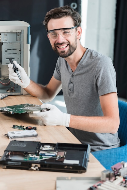 Foto gratuita retrato de un técnico de sexo masculino feliz que trabaja en la placa madre del ordenador