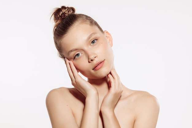 Retrato de tierna hermosa joven con maquillaje desnudo posando aislada sobre fondo blanco de estudio Belleza natural