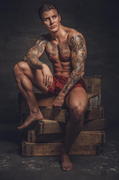 Retrato de un tipo musculoso desnudo con tatuajes en su cuerpo.