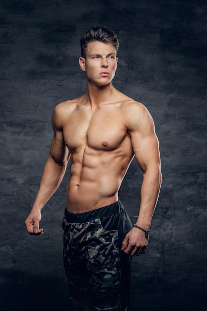 Retrato de un tipo musculoso fuerte sin camisa sobre fondo gris.