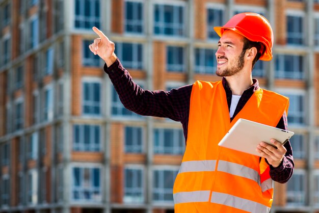 Retrato de tiro medio de arquitecto sonriente apuntando lejos