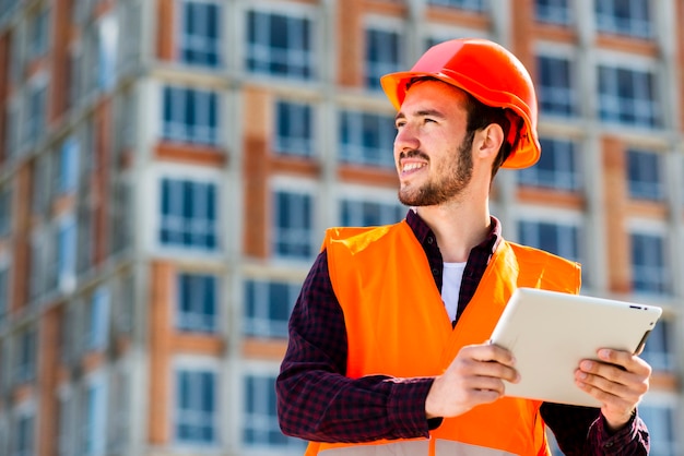 Retrato del tiro medio del ingeniero de construcción que sostiene la tableta