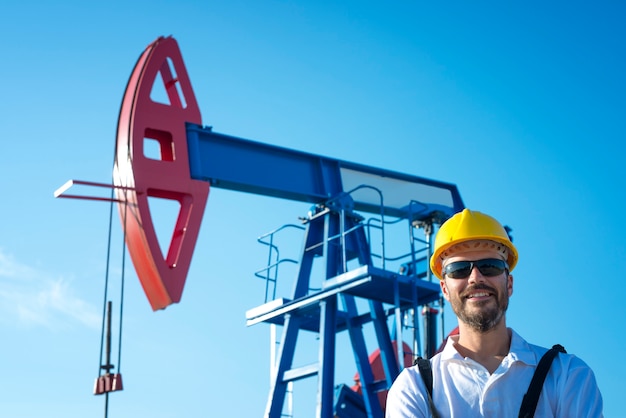 Retrato de un trabajador del campo petrolero de pie junto a la plataforma