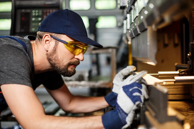 Retrato de trabajador cerca de la máquina metalúrgica