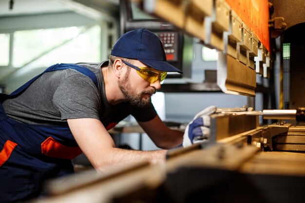 Retrato de trabajador cerca de la máquina metalúrgica