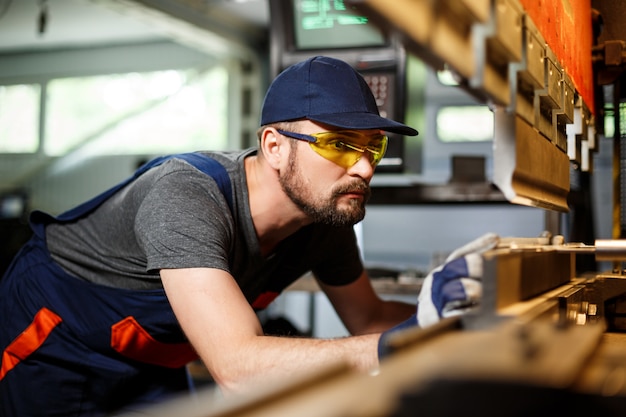 Retrato de trabajador cerca de la máquina metalúrgica