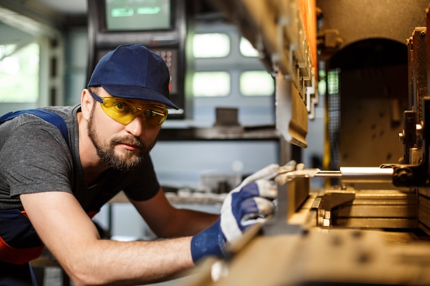 Retrato de trabajador cerca de la máquina metalúrgica