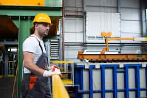 Foto gratuita retrato de trabajador de fábrica masculino apoyado en barandas de metal en la sala de producción industrial