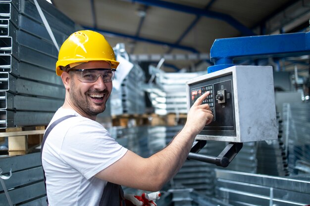 Retrato de trabajador de fábrica operando una máquina industrial y estableciendo parámetros en la computadora