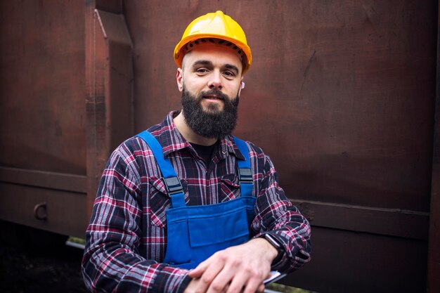 Retrato de trabajador ferroviario de pie por tren vagón de mercancías