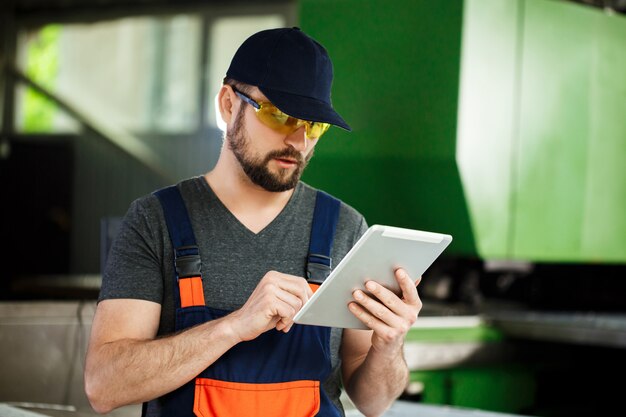 Retrato del trabajador en monos, fondo de la fábrica de acero.