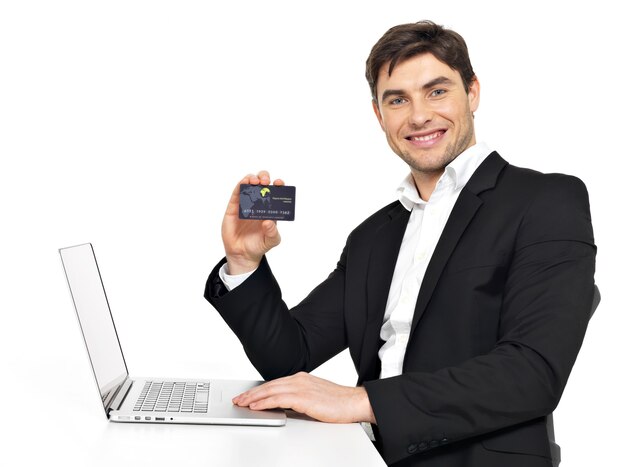 Retrato de trabajador de oficina con ordenador portátil y tarjeta de crédito sentado en la mesa aislada en blanco.