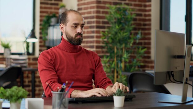 Retrato de un trabajador de oficina que usa una computadora para desarrollar análisis, creando tablas y gráficos comerciales para ayudar con el crecimiento financiero. Empleado masculino que trabaja en un proyecto de comercio electrónico con estadísticas.