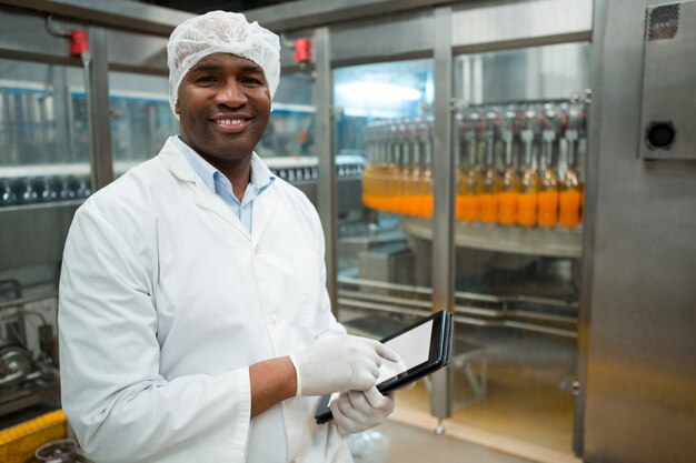 Retrato de trabajador varón sosteniendo tableta digital en la fábrica.