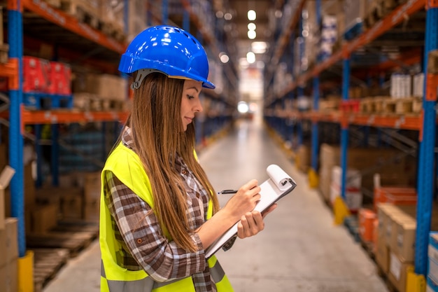 Foto gratuita retrato de trabajadora en almacén de distribución tomando notas