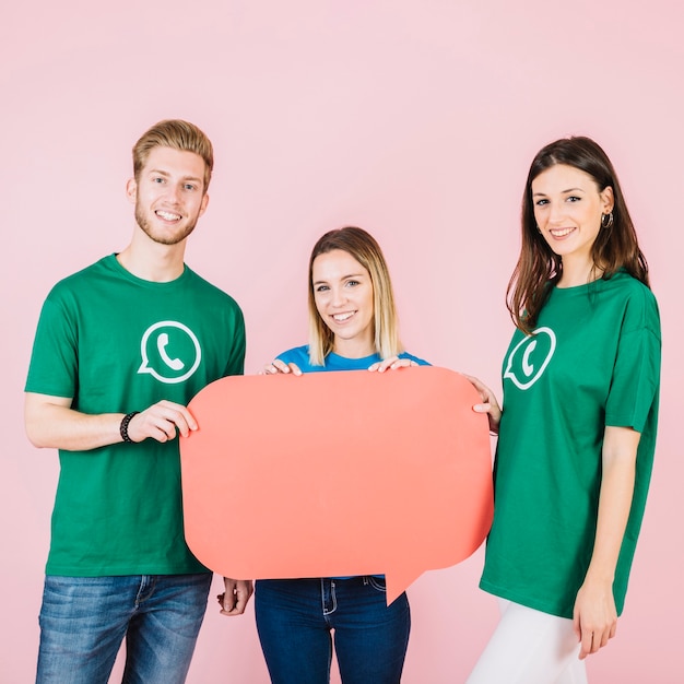 Foto gratuita retrato de tres amigos felices sosteniendo el bocadillo de diálogo verde vacío