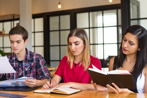 Retrato de tres estudiantes serios que estudian en la biblioteca