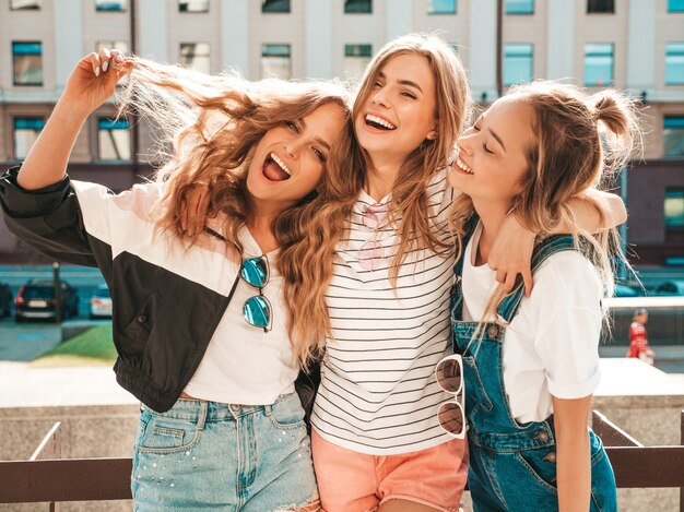 Retrato de tres jóvenes hermosas chicas hipster sonrientes en ropa de moda de verano. Mujeres despreocupadas y sexy posando en la calle. Modelos positivos divirtiéndose.