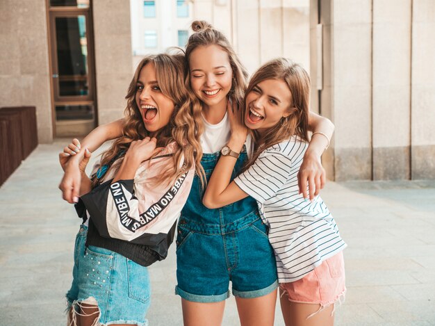 Retrato de tres jóvenes hermosas chicas hipster sonrientes en ropa de moda de verano. Mujeres despreocupadas y sexy posando en la calle. Modelos positivos divirtiéndose.