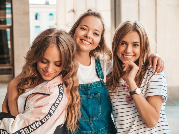 Retrato de tres jóvenes hermosas chicas hipster sonrientes en ropa de moda de verano. Mujeres despreocupadas y sexy posando en la calle. Modelos positivos divirtiéndose.