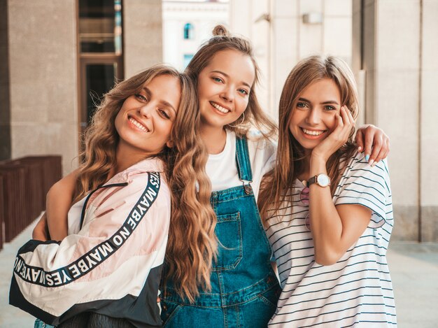 Retrato de tres jóvenes hermosas chicas hipster sonrientes en ropa de moda de verano. Sexy mujer despreocupada posando en la calle. Modelos positivos divirtiéndose