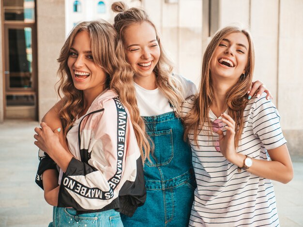 Retrato de tres jóvenes hermosas chicas hipster sonrientes en ropa de moda de verano. Sexy mujer despreocupada posando en la calle. Modelos positivos divirtiéndose