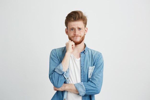 Retrato de triste joven molesto con la mano en el mentón.