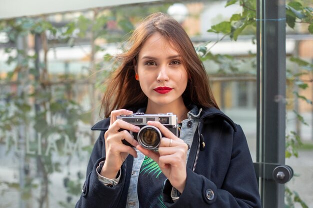 Retrato de un turista bastante joven tomando fotografías con una cámara retro vintage. Estilo callejero. Estilo de vida