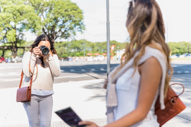 Retrato de un turista femenino que toma la fotografía de su amiga de la cámara